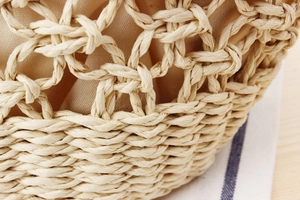 Detailed macro view of beige woven paper straw bag with hollow crochet pattern and fabric lining