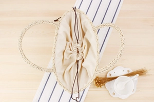 Detail view of woven handbag featuring beige fabric lining and brown drawstring closure