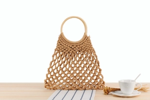 Detail der handgewebten Baumwoll-Netztasche mit runden Holzgriffen auf einem Tisch
