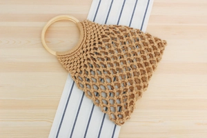 Detailed close-up of handmade woven cotton rope bag with circular wooden handles