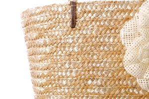 Close-up of tightly woven straw tote featuring white mesh 3D floral accents for summer