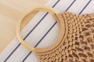 Detailed close-up of woven cotton rope texture and circular wooden handle on macrame bag