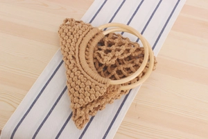 Detail of handmade beige macrame woven bag featuring elegant round wooden handles