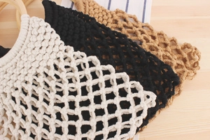 Detail of hand-woven mesh bags with wooden handles in cream, black, and brown