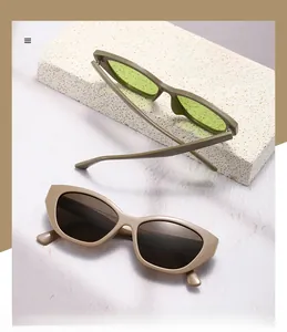 Detail view of cat eye sunglasses in green and khaki frames on white stone background