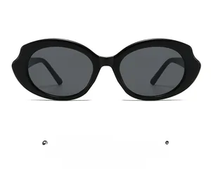 Détail de la monture ovale ondulée noire brillante et des verres noirs des lunettes de soleil