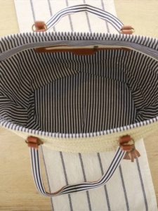 Woven straw tote bag with blue striped lining and brown leather tassel handle straps