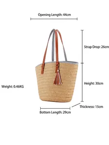 Handwoven straw tote bag with brown leather handles and tassel fringe for beach vacations