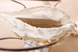 Detailed top view of straw handbag interior showing white linen lining and drawstring closure
