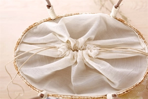 Detailed top view of handmade straw handbag with white drawstring lining and rope handles