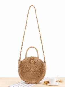 Handmade circular straw bag with top handles and shoulder strap on wooden background