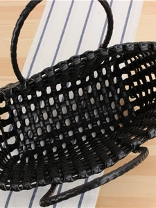 Minimalist black woven PVC tote bag with sturdy handles on a wooden table setting