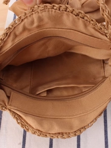 Internal view of khaki woven crossbody bag with zipper closure and fabric lining
