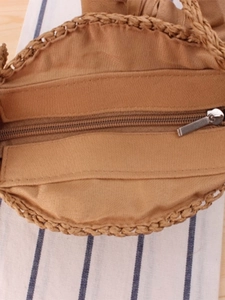 Handmade woven round straw bag with secure zipper closure and soft fabric lining detail