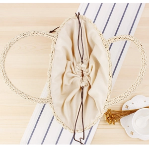 Handcrafted beige straw bag with fabric lining and drawstring closure for beach vacations