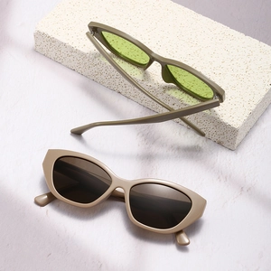Fashionable slim cat eye sunglasses in olive green and beige colors on stone background
