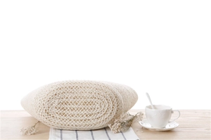 Detailed base view of an ivory woven beach bag showing refined texture on a rustic table