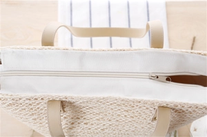 Close-up of woven straw handbag with silver zipper closure and premium PU handles