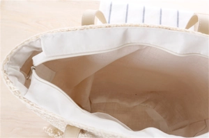 Detail view of woven tote bag with white cotton lining and silver metal zipper closure