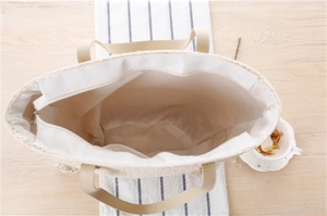 Top view of woven straw beach tote showing spacious white lining and silver zipper closure