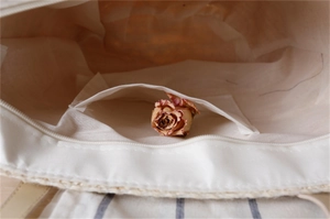 Detail of woven straw bag interior featuring white fabric lining and a smooth metal zipper