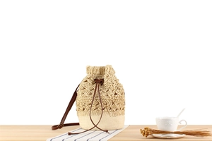 Close-up of hollowed-out straw bucket bag with leather drawstring and textured weave