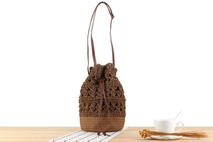 Detail of hollow-out paper rope woven bucket bag with leather drawstring and strap