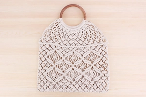 Dettaglio borsa macramè bohémien bianco sporco con manici circolari in legno marrone