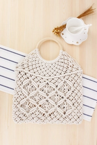 Dettaglio della borsa bohémien in cotone intrecciato crema con manici tondi in legno