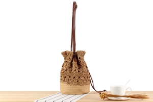Detailed close-up of handmade woven straw bucket bag with diamond hollow patterns