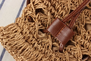 Macro detail of paper rope weave and leather drawstring closure on beach bucket bag