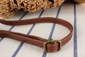 Detail of adjustable brown leather strap with antique bronze buckle on woven bag
