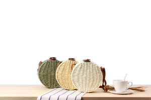 Detailed close-up of woven round straw bags in green, beige, and white with leather straps