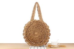Close-up of circular hand-woven straw bag with lace edges on a rustic wooden table
