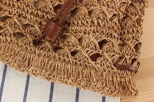 Close-up of hollow paper rope weave texture and brown leather drawstring on a bucket bag