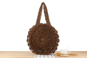 Detailed view of dark brown round straw woven bag with bohemian scalloped edge pattern