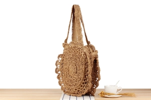 Close-up of a handmade round straw tote bag with intricate hollow-out lace patterns