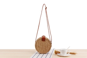 Detail of round straw crossbody bag with leather flap and vintage rivet decoration