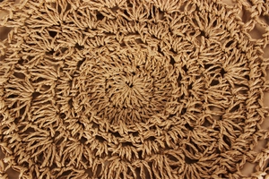 Macro detail of radial hand-woven circular pattern on brown paper rope shoulder bag