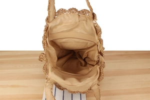 Interior detail of straw woven shoulder bag showing zipper pocket and fabric lining