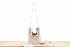 Détail de la texture crochet crème et de la courbe en U du sac à bandoulière tissé