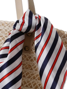 Striped satin scarf in red white and blue tied to a woven beach tote handle