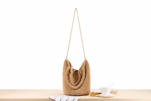 Détail d'un sac cabas tissé cylindrique avec doubles poignées sur table en bois