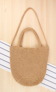 Détail d'un sac cabas tissé main avec doubles poignées sur fond en bois rustique