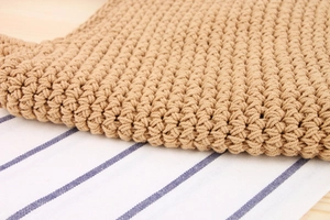 Gros plan sur la texture tissée d'un sac à bandoulière bohème kaki en cordes de coton