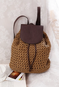 Detail of woven straw texture and dark brown faux leather straps on bohemian backpack