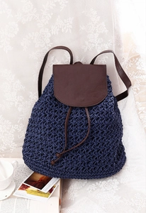 Detail of blue paper straw backpack with brown leather flap on floral lace fabric