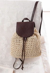 Detail of hand-woven straw backpack with brown leather flap and secure drawstring closure