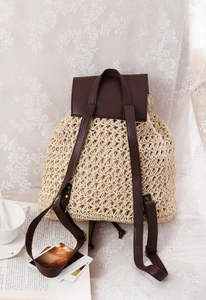 Detailed view of beige paper rope woven backpack with brown leather lid and drawstring closure