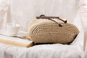 Detail of woven straw backpack with brown leather drawstrings and lid in casual setting